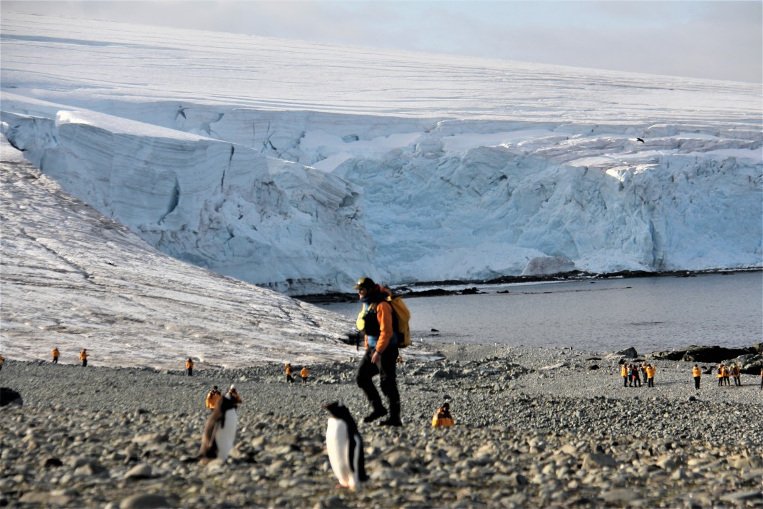 Expedition crew with penguin and glacier